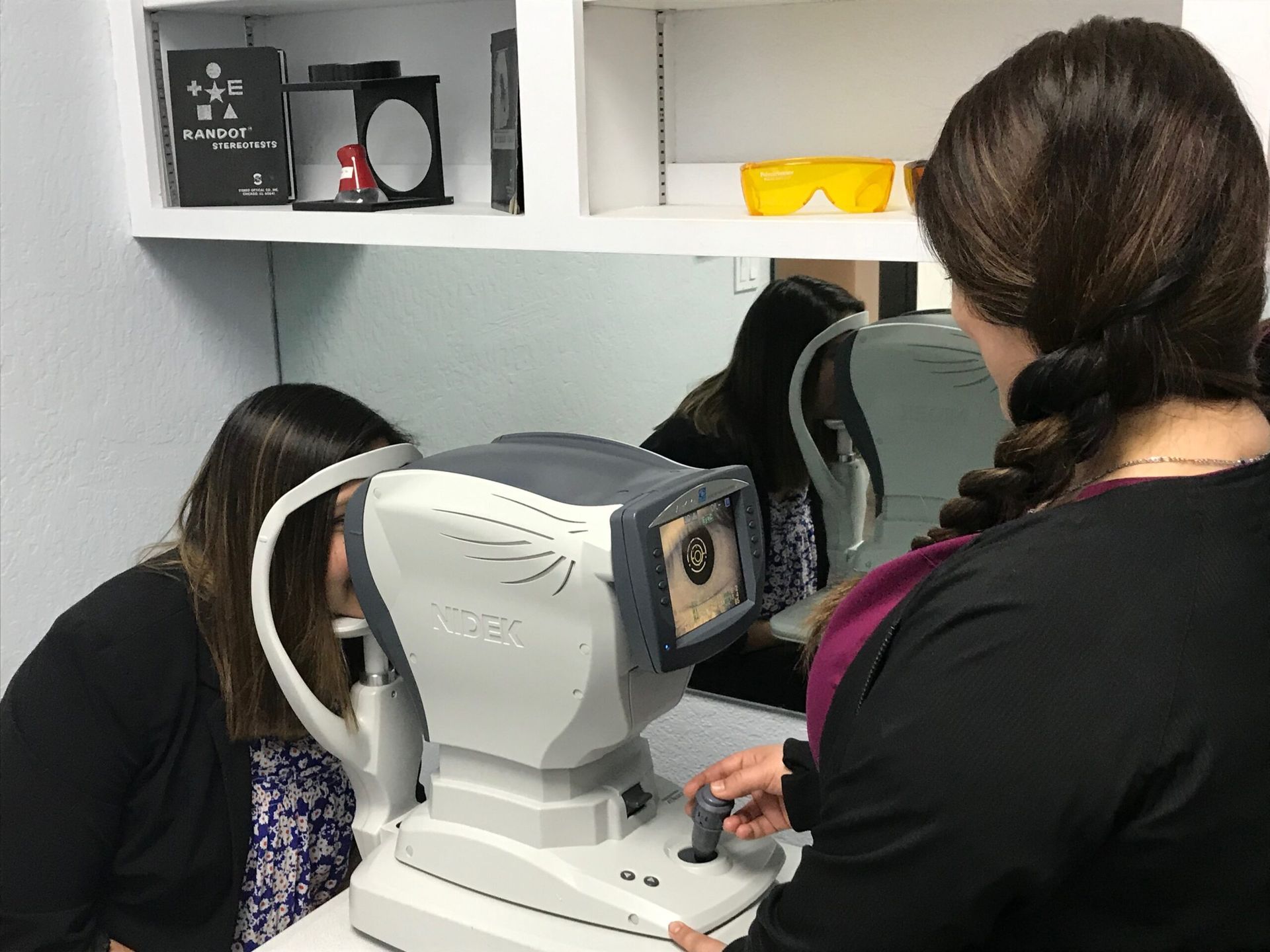 Patient at an autorefractor while staff take preliminary measurements